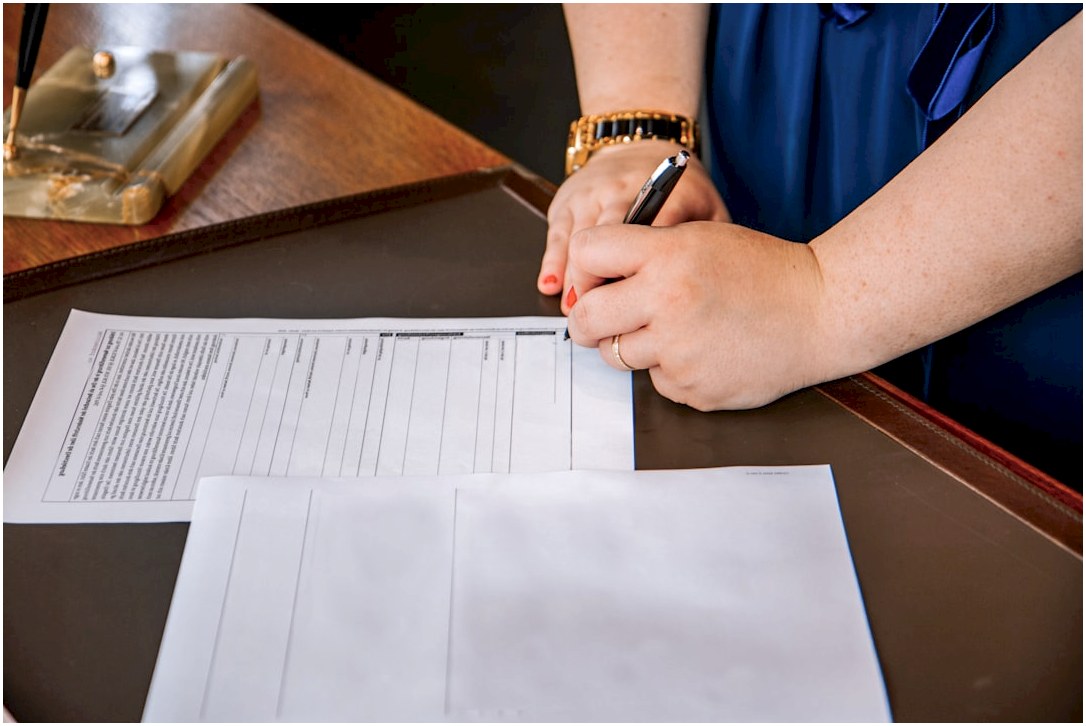 person holding pen and writing on paper