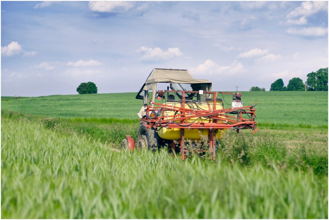 red and yellow tractor on green grass field under white clouds during daytime