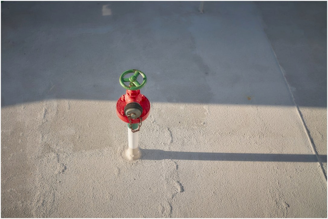 A red and green fire hydrant sitting on the side of a road
