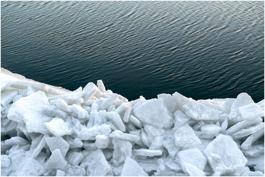 Pile of ice chunks by dark rippling water