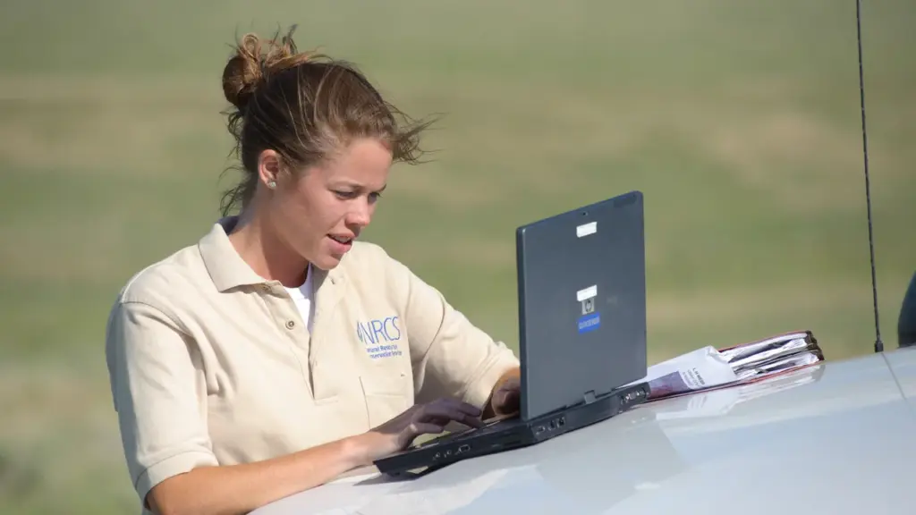 Técnica consulta computador durante assistência em área rural
