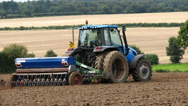 Trator com semeadora trabalhando em área preparada para plantio