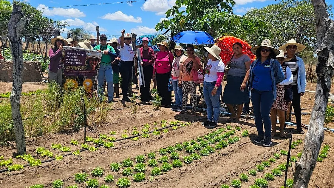 Mulheres rurais ao lado de horta comunitária em atividade de agricultura familiar