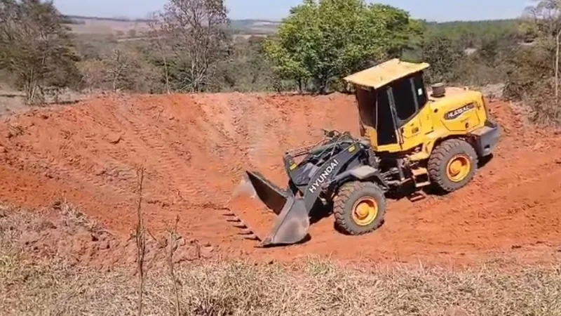 Máquina trabalhando na abertura de uma barraginha em área rural de Divinópolis