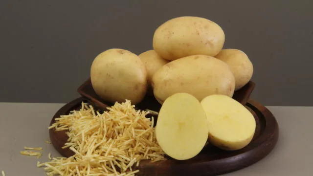Batatas inteiras e cortadas ao lado de batata palha em prato de madeira