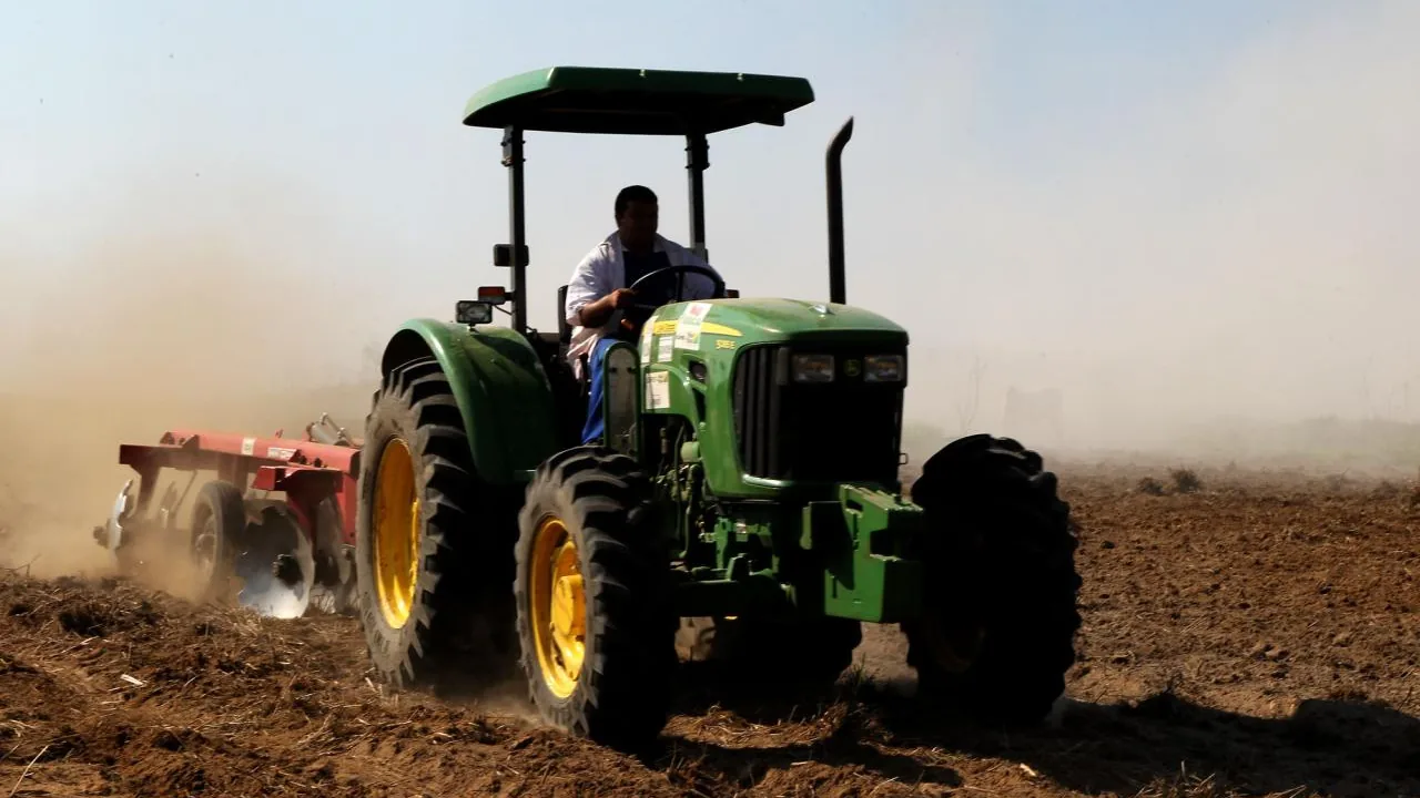 Trator trabalha o solo de uma propriedade rural, imagem contextual para o Crédito Fundiário
