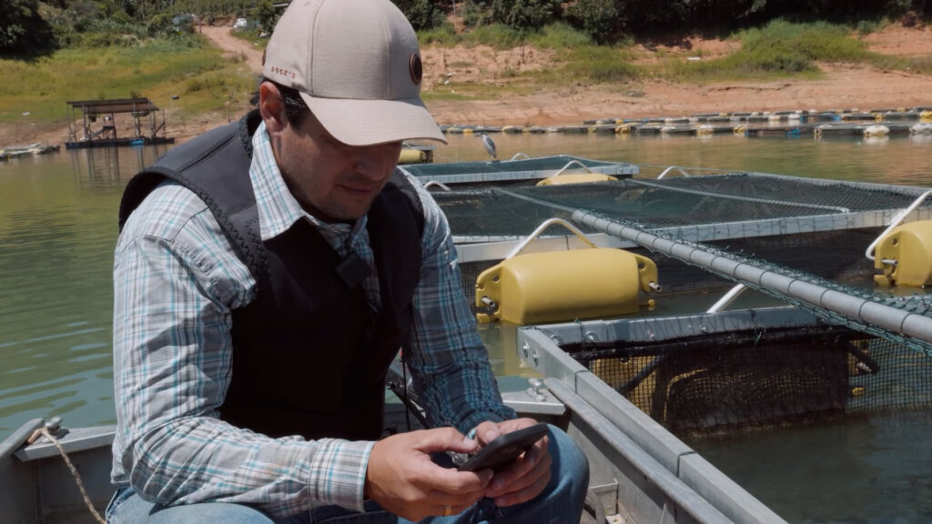 Produtor rural observa equipamento digital durante atividade no campo