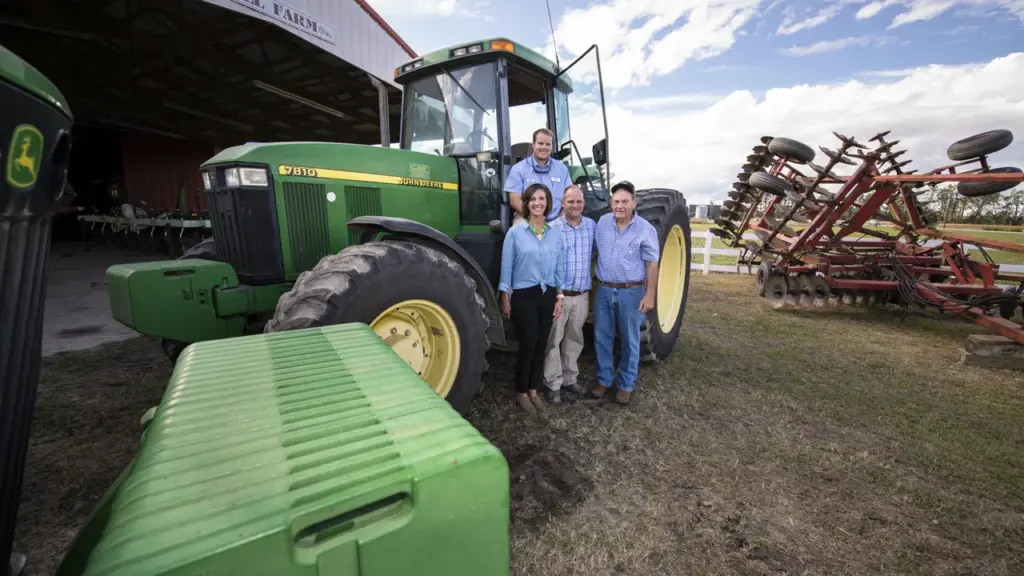 Trator e produtores rurais junto a implemento agrícola em uma propriedade