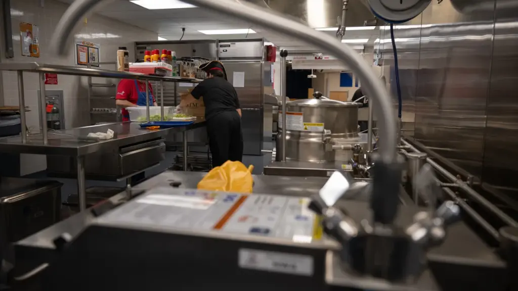 Equipe prepara alimentação em cozinha escolar