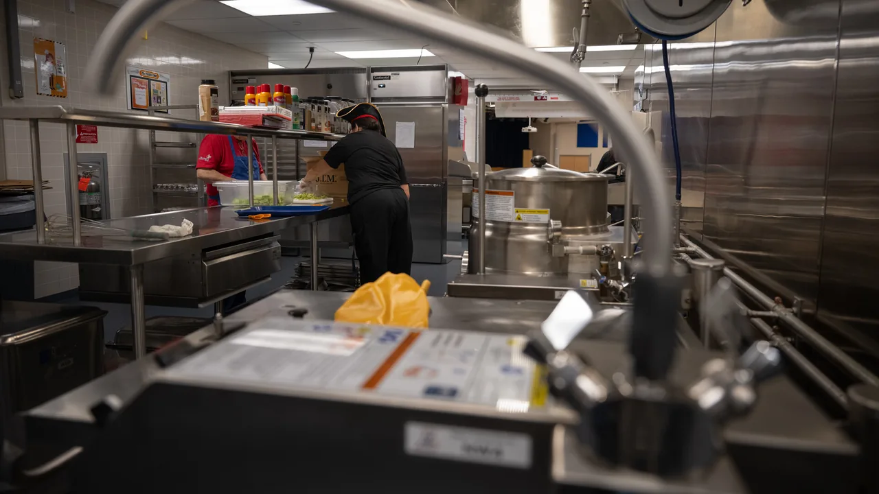 Equipe prepara alimentação em cozinha escolar